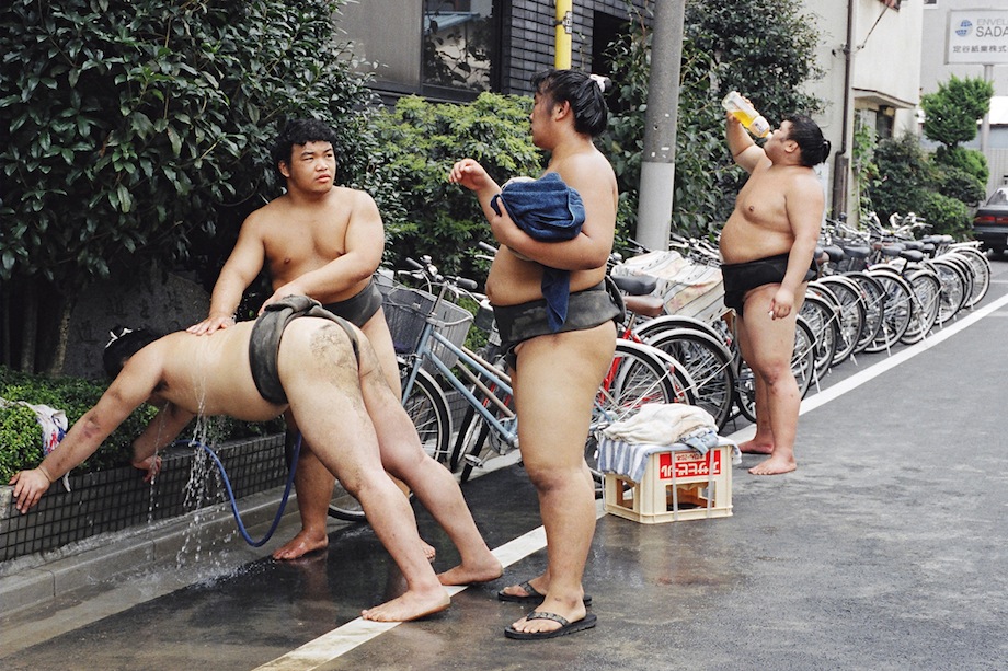 Rishiki (wrestlers) wash themselves with a hose outside Musashigawa-beya.