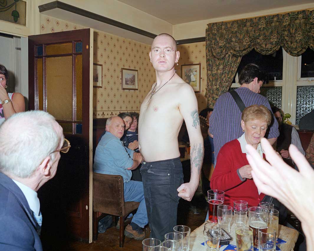 A bare chested skinhead postures for the camera in a pub in Bacu