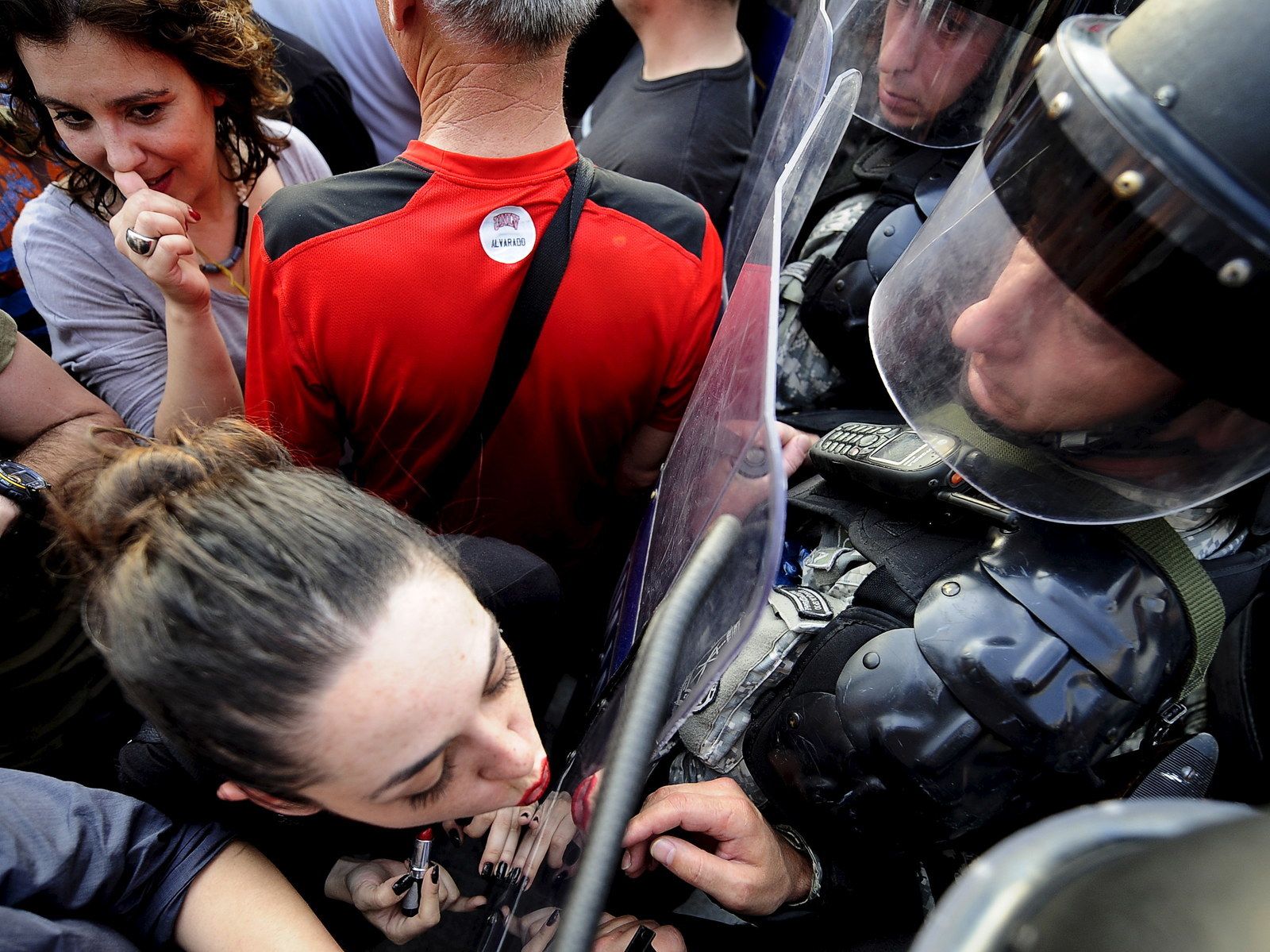 A girl puts on lipstick and kisses the shield of the police in front of the Macedonian government building in Skopje, Macedonia