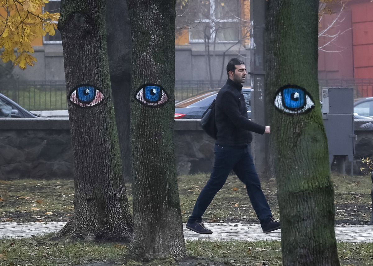 A man walks past trees painted with eyes in a park in central Kiev, Ukraine, November 17, 2015.  REUTERS/Gleb Garanich - RTS7IHD