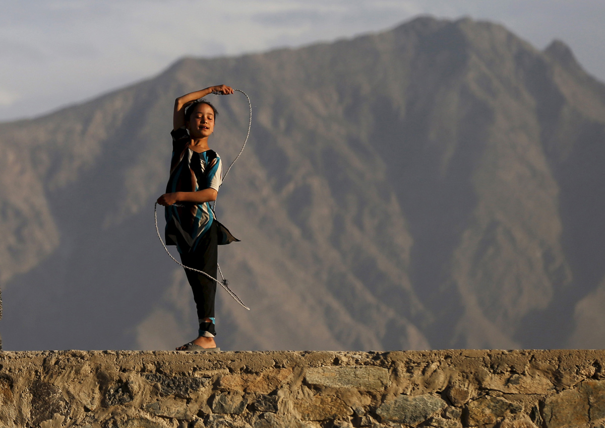 An Afghan girl plays with a rope on a hilltop in Kabul