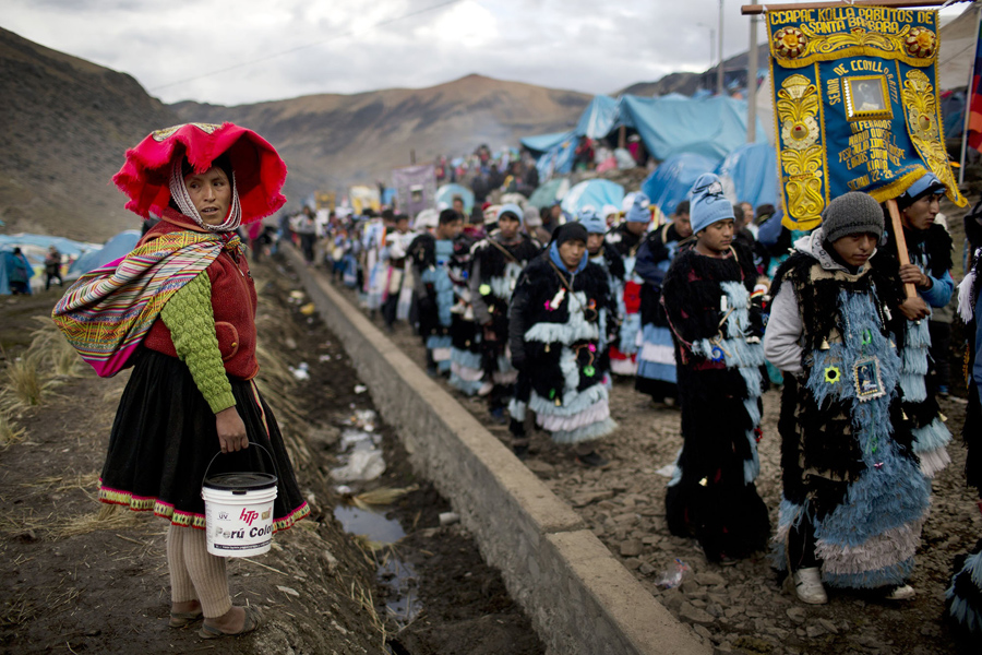 In this May 23, 2016 photo, a Quechua woman waits for a religious procession to file past so she can cross the road, during the second day of the syncretic festival Qoyllur Rit’i, translated from the Quechua language as Snow Star, in the Sinakara Valley, in Peru's Cusco region. The festival coincides with the reappearance of the star cluster Pleiades in the Southern Hemisphere, signaling the harvest season. (AP Photo/Rodrigo Abd)