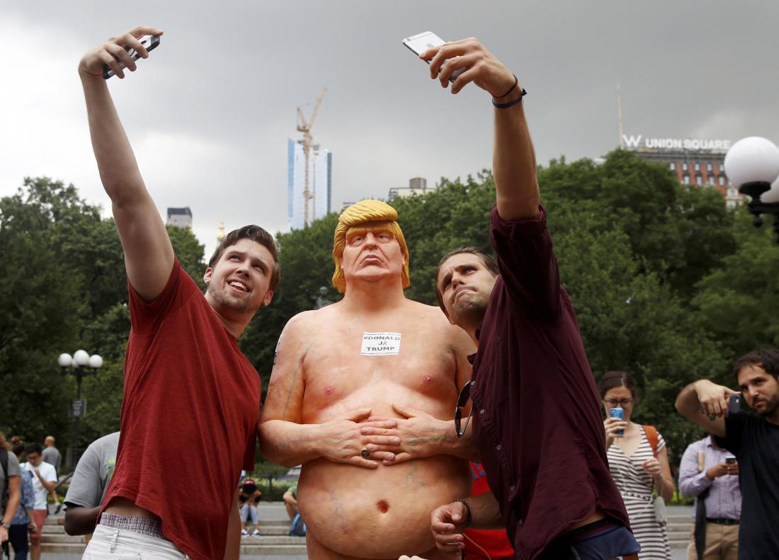 People pose for selfies with a naked statue of U.S. Republican presidential nominee Donald Trump that was left in Union Square Park in New York City, U.S. August 18, 2016. REUTERS/Brendan McDermid FOR EDITORIAL USE ONLY. NO RESALES. NO ARCHIVES