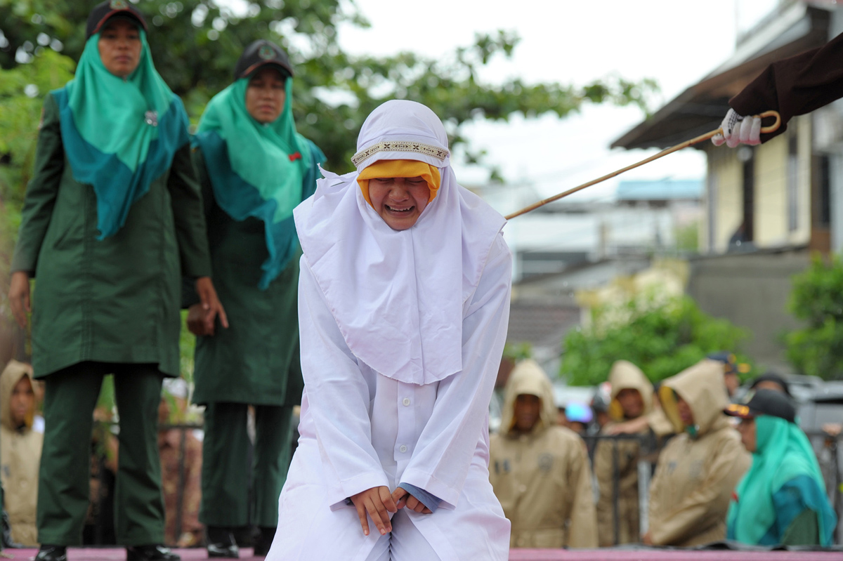 CORRECTION - A Muslim woman gets caned 23 strokes after being caught in close proximity with her boyfriend in Banda Aceh on October 17, 2016. Out of seven couples caught spending time together outside marriage, 13 were caned while one woman was spared after it was discovered that she was pregnant. Indonesia's Aceh province has gained international infamy for its strict Islamic laws. / AFP / CHAIDEER MAHYUDDIN / The erroneous mention[s] appearing in the metadata of this photo by CHAIDEER MAHYUDDIN has been modified in AFP systems in the following manner: [WOMAN] instead of [GIRL]. Please immediately remove the erroneous mention[s] from all your online services and delete it (them) from your servers. If you have been authorized by AFP to distribute it (them) to third parties, please ensure that the same actions are carried out by them. Failure to promptly comply with these instructions will entail liability on your part for any continued or post notification usage. Therefore we thank you very much for all your attention and prompt action. We are sorry for the inconvenience this notification may cause and remain at your disposal for any further information you may require. (Photo credit should read CHAIDEER MAHYUDDIN/AFP/Getty Images)